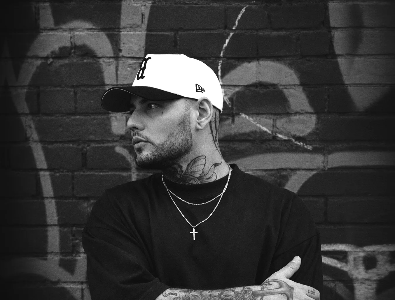 Tattoo artist Bruno Samuel standing in front of a painted brick wall
